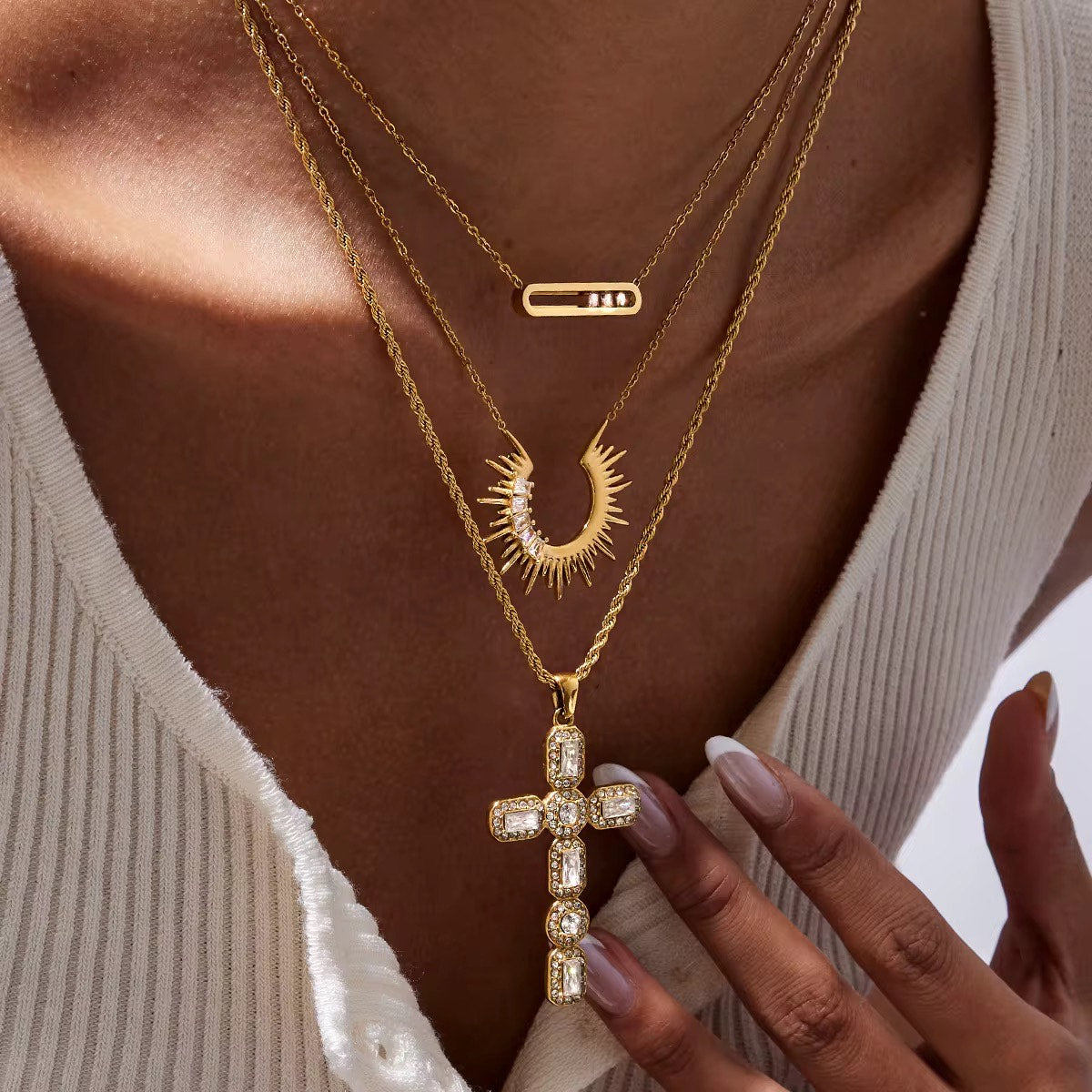 Gold necklace with a cross pendant worn by a person
